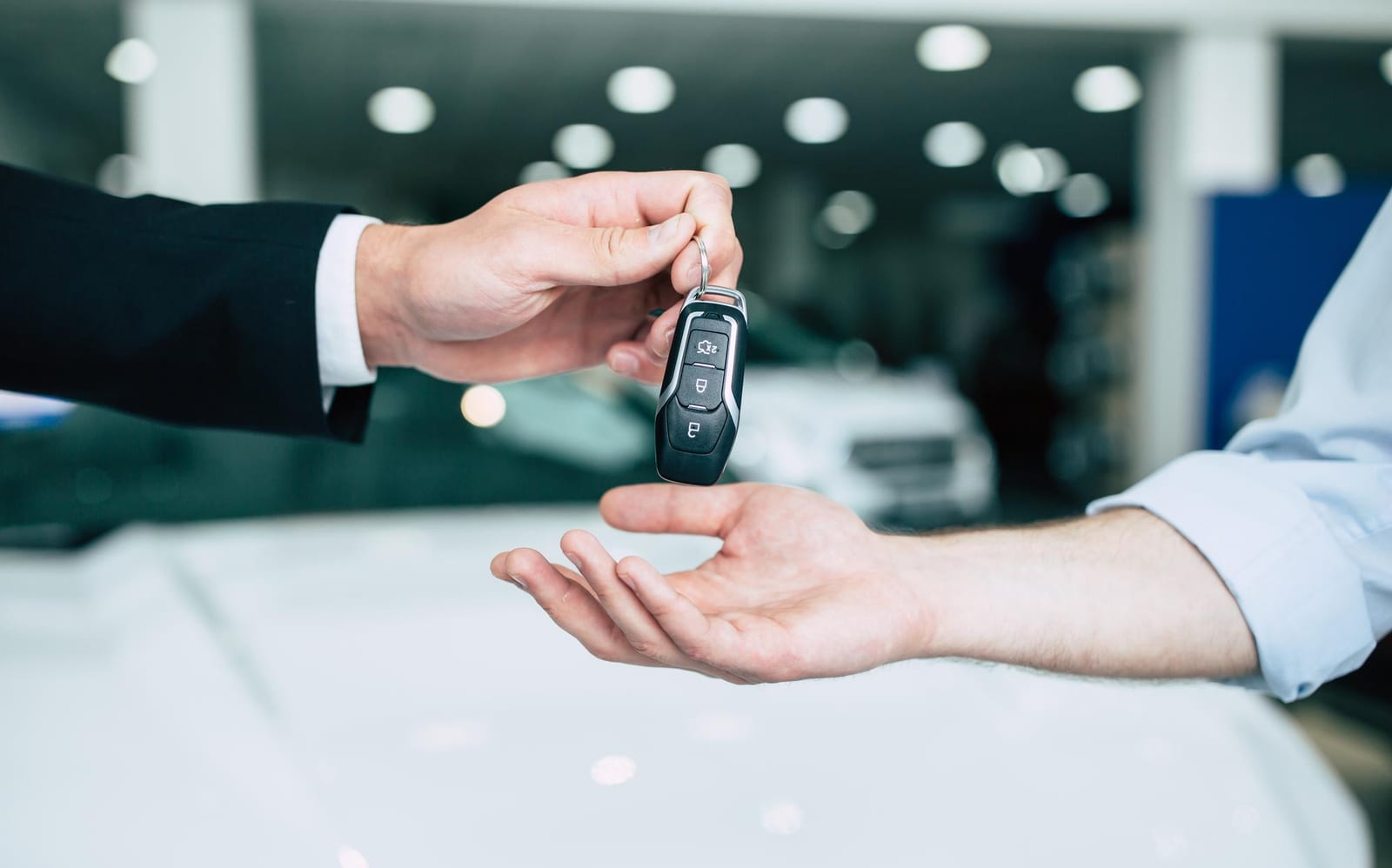 Um vendedor entrega a chave de um carro a um comprador em um showroom.